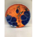 Poole pottery charger with blue painted flowers on orange washed ground, with stamp verso 40cm