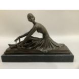 A reproduction Art Deco bronze-effect figure after Chiparus of a female dancer sitting tying the