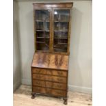 An early 20th Century mahogany and walnut bookcase with hinged fold down front opening to reveal