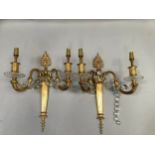 A set of six gilt metal twin light wall sconces each as a torchere with anthemion cresting, leaf