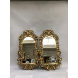 A pair off reproduction gilt, heavily carved and moulded reproduction wall mirrors adorned with