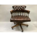 A reproduction oak button back captains chair in tan leather, on turned support, on four legs on