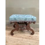 A Victorian mahogany heavily carved stool with c-scroll legs joined by turned supports,