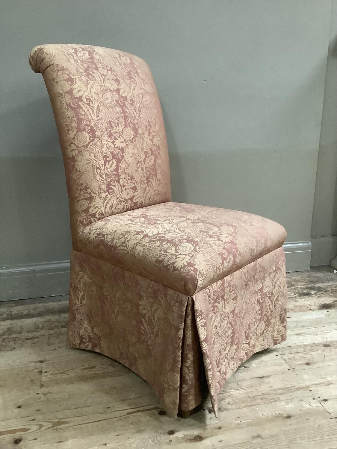 A bedroom chair upholstered in pink and gold fabric with skirt