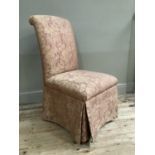A bedroom chair upholstered in pink and gold fabric with skirt