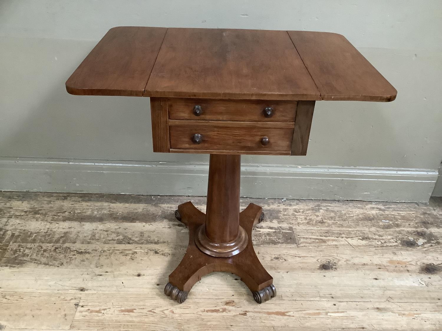 A Victorian rosewood work table with two drop leaves, two long drawers, on column supports with