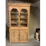 A reclaimed pine bookcase with two glazed doors revealing four internal shelves above two cupboard