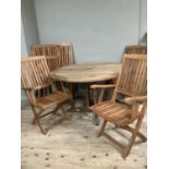 A circular folding garden dining table with six chairs and cushions