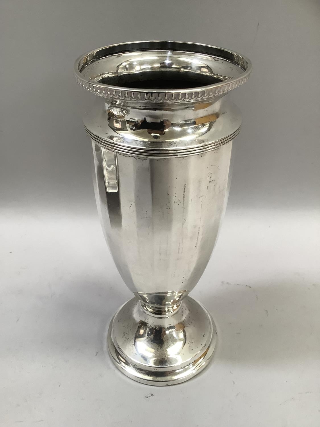 A silver vase of panelled and tapered form on a circular stepped and weighted base, 18cm high,