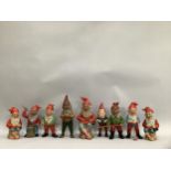 Nine painted garden gnomes including one cast metal and porcelain examples, three holding