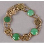 A JADE BRACELET C1950 in 14ct gold, the circular cabochon stones collet set alternating with pierced