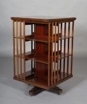 AN EARLY 20th CENTURY MAHOGANY REVOLVING BOOKCASE of three tiers and railed panels on quadruple