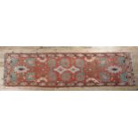 A MIDDLE EASTERN RUNNER of coral ground with opposing lotus and medallion pattern in turquoise and