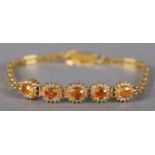 A YELLOW SAPPHIRE AND DIAMOND BRACELET, the oval faceted sapphires claw set, raised against a