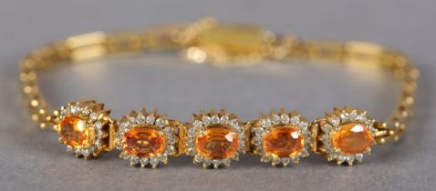 A YELLOW SAPPHIRE AND DIAMOND BRACELET, the oval faceted sapphires claw set, raised against a