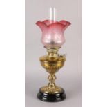 A VICTORIAN BRASS OIL LAMP, with wrythen lobed reservoir and scrolled base on a black glass