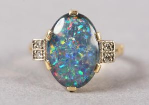 AN BLACK OPAL DOUBLET AND DIAMOND RING C1950 in 18ct gold, the oval cabochon stone claw set