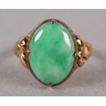 A JADE DRESS RING C1950 in 14ct gold the oval cabochon stone claw set and flanked by applied foliate