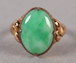 A JADE DRESS RING C1950 in 14ct gold the oval cabochon stone claw set and flanked by applied foliate