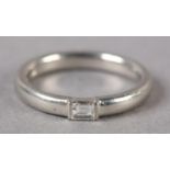 A SINGLE STONE DIAMOND RING in platinum channel set with a baguette cut stone, approximate weight of