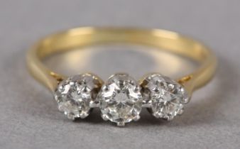 A THREE STONE DIAMOND RING in 18ct yellow and white gold, the graduated brilliant cut stones claw