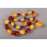 AN AMBER NECKLACE C.1920S of graduated oval beads, alternating deep red and butterscotch in