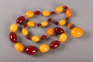 AN AMBER NECKLACE C.1920S of graduated oval beads, alternating deep red and butterscotch in