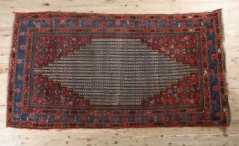 A MIDDLE EASTERN RUG, the wine coloured field having a stepped lozenge medallion filled with