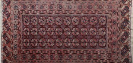 A BOKHARA SILK RUG, the wine field filled with three rows of ten elephant foot medallions within a