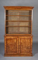 A MID-19TH CENTURY FIGURED WALNUT BOOKCASE-CUPBOARD, having a moulded cornice above three open