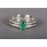 AN EMERALD AND DIAMOND RING IN 18CT WHITE GOLD, claw set to the centre with a step cut emerald