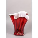 A GLASS VASE OF FAZZOLETTO FORM the exterior in reds and oranges with white interior, the glass