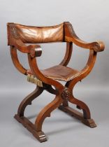 A LATE 19TH CENTURY FRUITWOOD FOLDING 'X' FRAME CHAIR, having a hide sling back, leaf carved arms