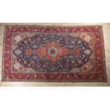 A MIDDLE EASTERN CARPET, Persian, the blue field filled with plant motifs centred with a coral