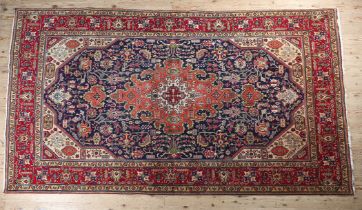 A MIDDLE EASTERN CARPET, Persian, the blue field filled with plant motifs centred with a coral