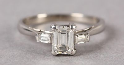 A THREE STONE DIAMOND RING, claw set to the centre with a step cut stone flanked by two baguette cut