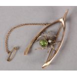 AN EDWARD VII PERIDOT AND PEARL SPIDER WISHBONE BROOCH in 9ct rose gold, collet set to the abdomen