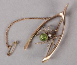 AN EDWARD VII PERIDOT AND PEARL SPIDER WISHBONE BROOCH in 9ct rose gold, collet set to the abdomen