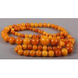 AN EARLY 20TH CENTURY AMBER NECKLACE of graduated spherical beads, approximate maximum diameter