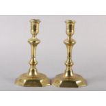 A PAIR OF EARLY 18TH CENTURY BRASS CANDLESTICKS, having a cylindrical sconce, inverted baluster stem