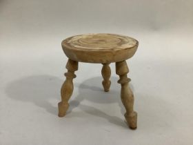 A pine apprentice milking stool on three turned legs, 14cm high