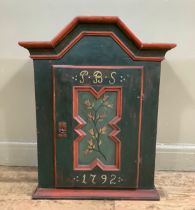 A green painted wall cabinet having an arched cornice above a single door with indented panel