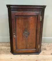 A 19th century oak corner hanging cupboard having a moulded cornice over a single door, H brass