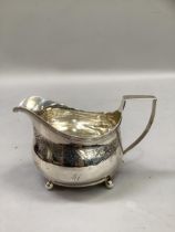 A George III silver cream jug, London 1811 (maker not registered), foliate engraved and monogrammed,