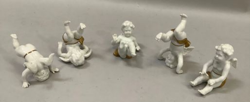 Five continental tumbling cherub figures white ground with gilt detailing, in various poses, bearing