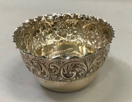 A silver bowl, circular having a folded rim above a deep border embossed with leaf curls,