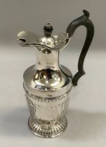 A silver hot water jug with ebonised scrolled handle and finial, the fluted body with cartouche,