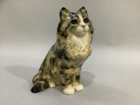 A pottery figure of a tabby cat by Jenny Winstanley with glass eyes, signed to base, 24cm high