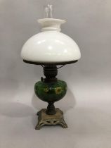 Edwardian oil lamp on an Art Nouveau style pierced metal base, the green glass reservoir painted