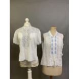Two fine white cotton lawn vintage blouses, the first sleeveless, the collar and bodice front panels